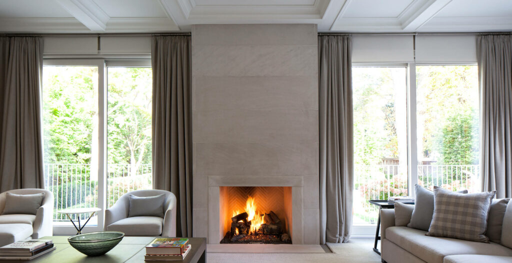 A fireplace flanked by floor to ceiling windows in a modern living room