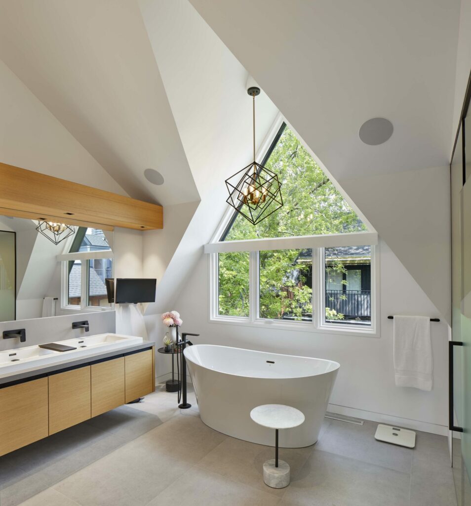 A large modern bathroom with vaulted ceilings, a floating vanity and stand alone tub