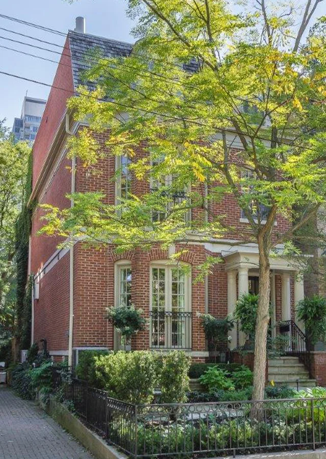 A red brick townhouse with a large tree outside